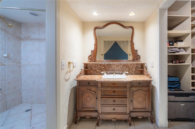 full bathroom with a textured wall, recessed lighting, a tile shower, and vanity