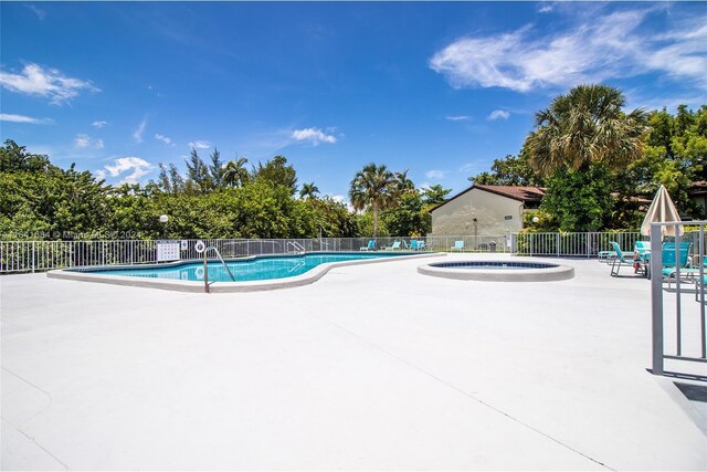 view of swimming pool featuring a hot tub and a patio area