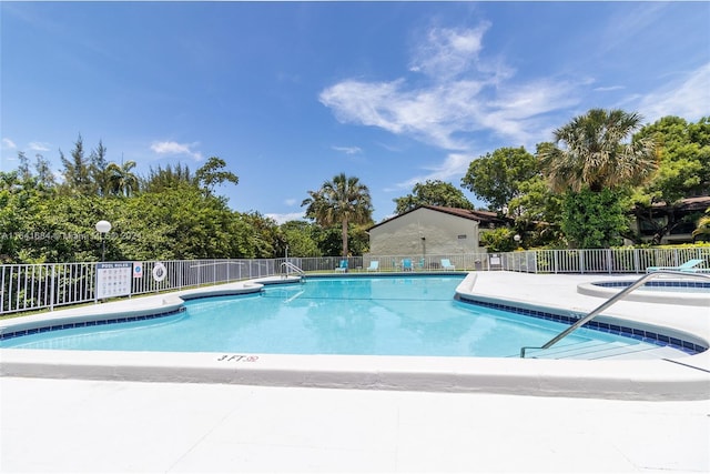 community pool with a patio area and fence