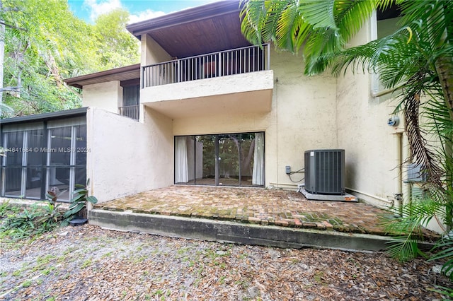 entrance to property featuring a patio, central AC unit, a balcony, and stucco siding