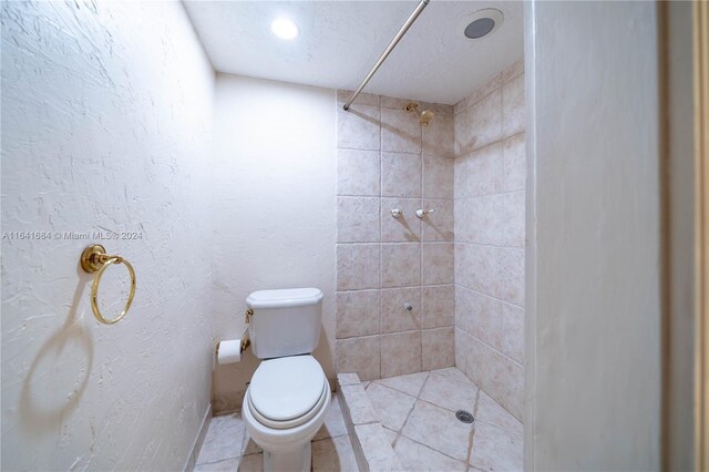 bathroom with a textured ceiling, toilet, a tile shower, and tile patterned flooring