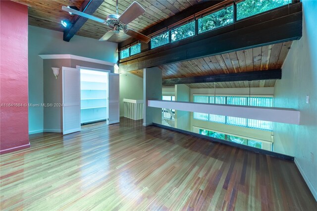 unfurnished living room with ceiling fan, vaulted ceiling with beams, wooden ceiling, and wood-type flooring