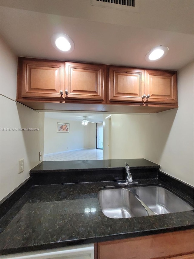 kitchen with sink, ceiling fan, and dark stone countertops