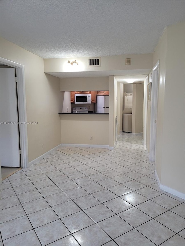 unfurnished living room with light tile patterned floors, a textured ceiling, and washer / dryer