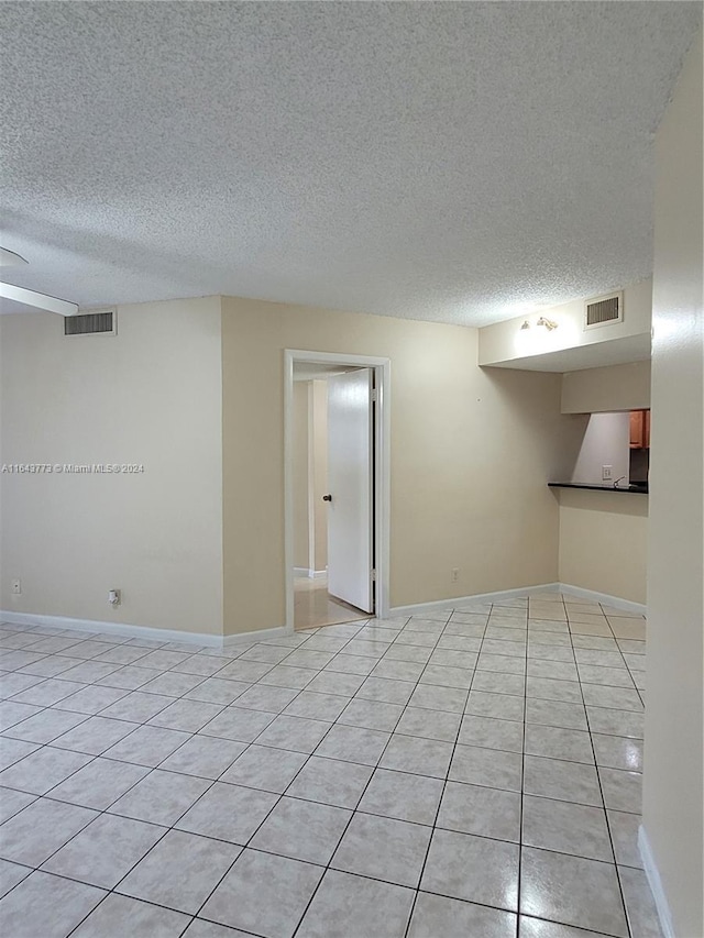 tiled empty room featuring a textured ceiling