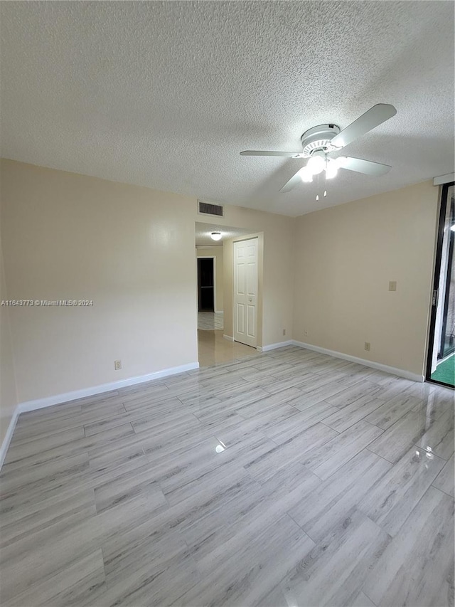 unfurnished room featuring ceiling fan, light hardwood / wood-style floors, and a textured ceiling