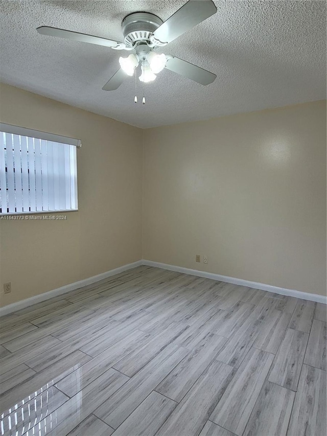 spare room with ceiling fan, light hardwood / wood-style flooring, and a textured ceiling