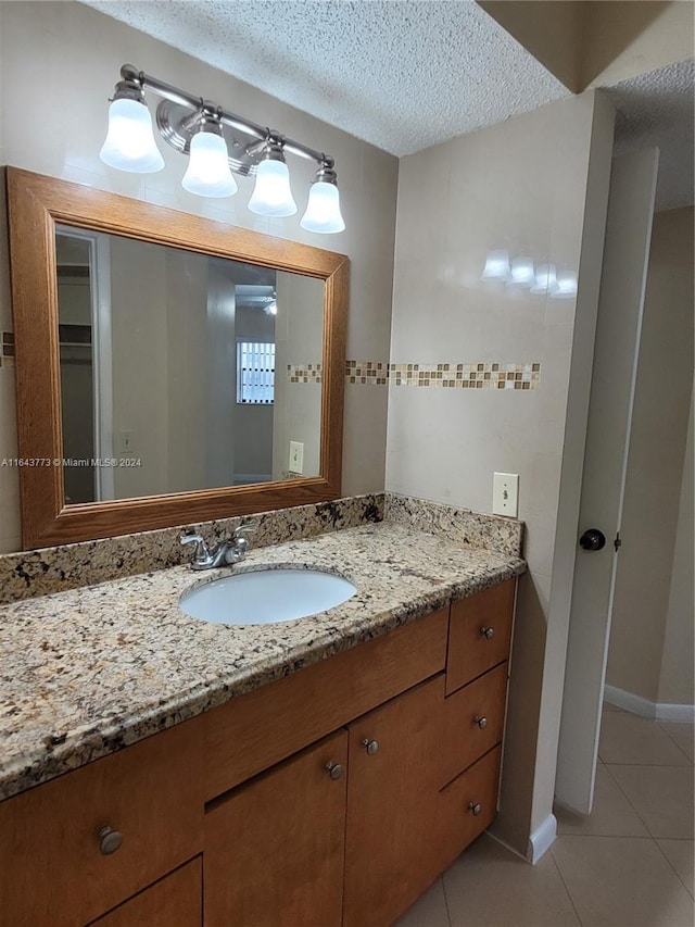 bathroom with tile patterned flooring, vanity, and a textured ceiling