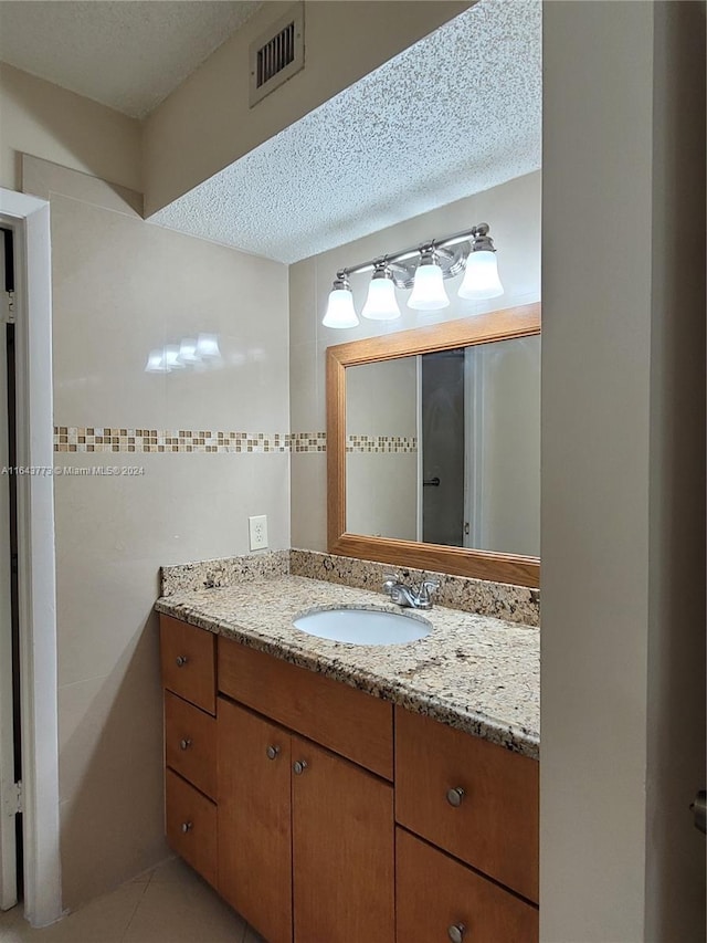 bathroom with tile patterned flooring, vanity, and a textured ceiling