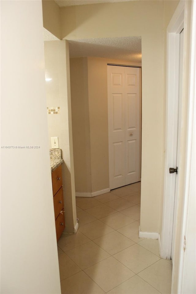 hall with light tile patterned flooring and a textured ceiling