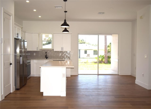 kitchen featuring a kitchen island, stainless steel fridge, pendant lighting, decorative backsplash, and white cabinets