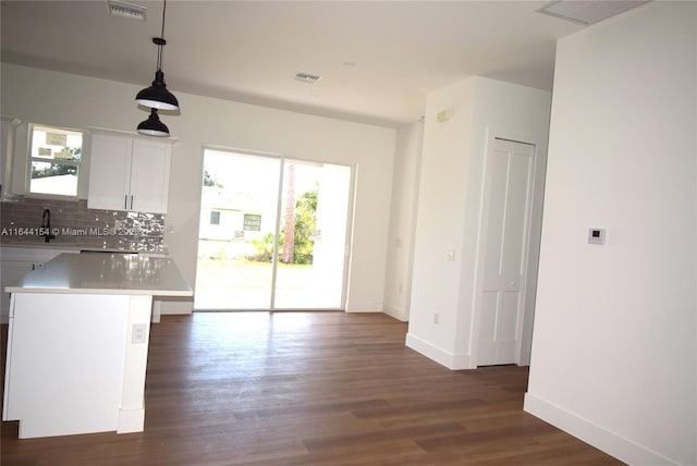 kitchen featuring white cabinetry, a center island, sink, dark wood-type flooring, and decorative light fixtures