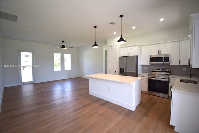 kitchen with white cabinetry, ceiling fan, hanging light fixtures, stainless steel appliances, and a kitchen island