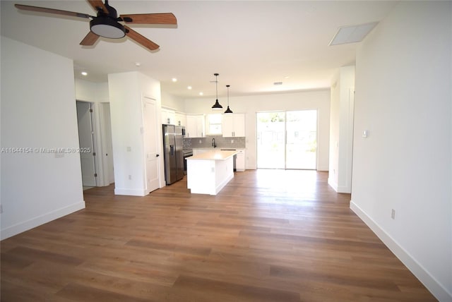 kitchen with decorative backsplash, a kitchen island, decorative light fixtures, stainless steel fridge with ice dispenser, and white cabinetry