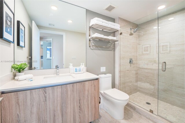 bathroom featuring vanity, toilet, and a shower with shower door