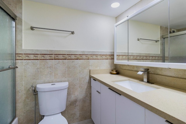 bathroom featuring tile walls, a shower with shower door, vanity, and toilet