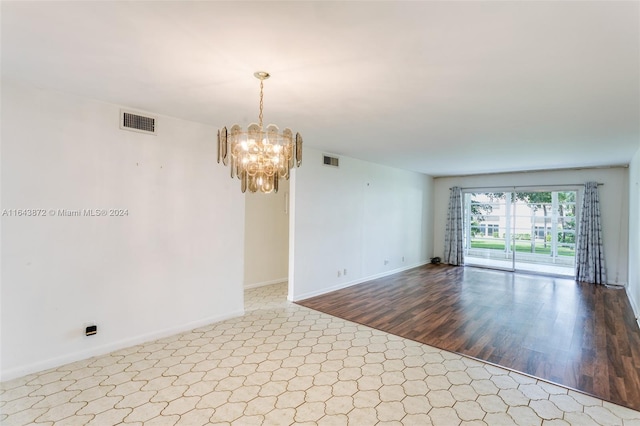 empty room featuring a chandelier and light wood-type flooring