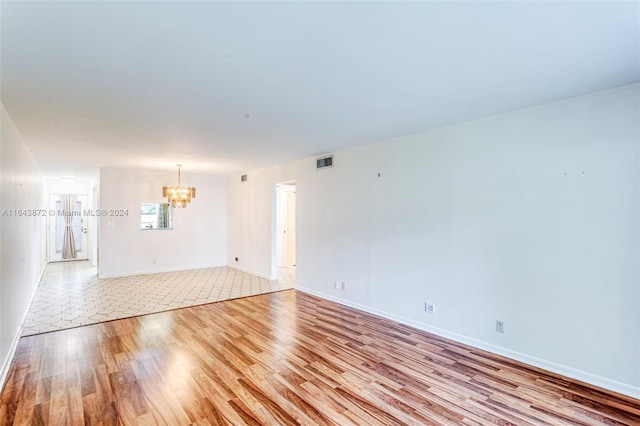 empty room featuring light hardwood / wood-style floors and an inviting chandelier