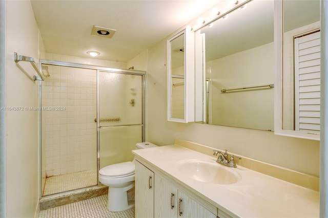 bathroom with toilet, vanity, tile patterned floors, and a shower with door