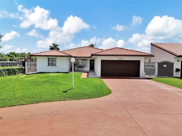 mediterranean / spanish house featuring a garage, fence, concrete driveway, stucco siding, and a front lawn