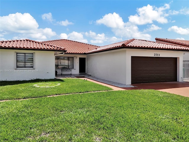 mediterranean / spanish-style home with a garage, a tile roof, a front lawn, and stucco siding