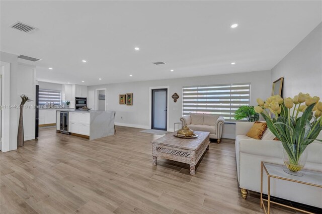 living room featuring sink, light hardwood / wood-style floors, and wine cooler