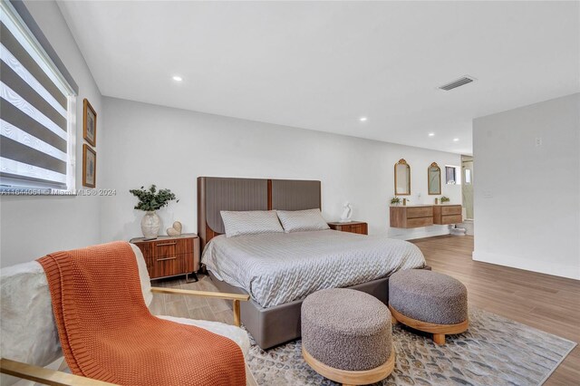 bedroom featuring ensuite bathroom and light hardwood / wood-style flooring