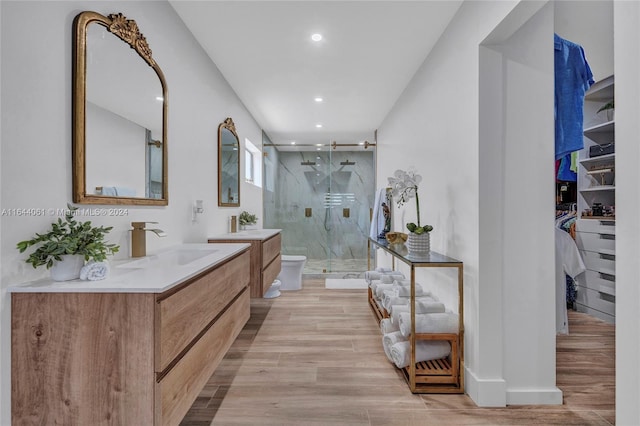 full bathroom featuring toilet, wood finished floors, vanity, a spacious closet, and a marble finish shower