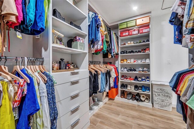 walk in closet with light hardwood / wood-style flooring