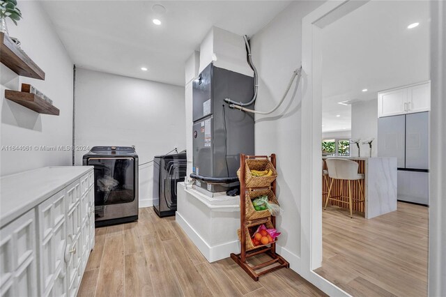 interior space featuring heating unit, light hardwood / wood-style flooring, and independent washer and dryer