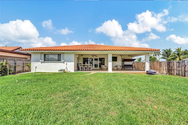 back of house featuring ceiling fan, a yard, and a patio