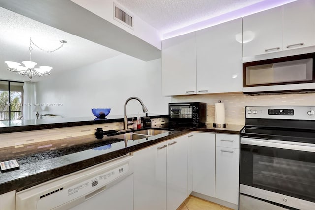 kitchen with dark stone counters, backsplash, a chandelier, appliances with stainless steel finishes, and sink