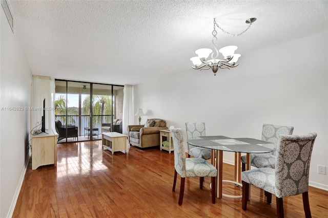 dining room with hardwood / wood-style flooring, an inviting chandelier, a textured ceiling, and floor to ceiling windows