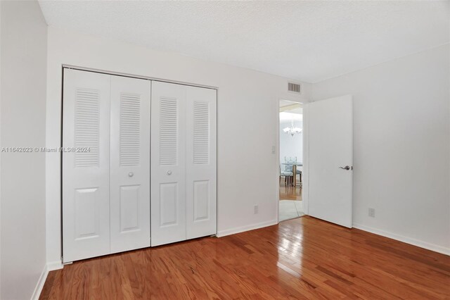 6219 Coral Lake Dr Unit 207, Margate, FL 33063 - unfurnished bedroom with baseboards, a chandelier, visible vents, a closet, and wood finished floors