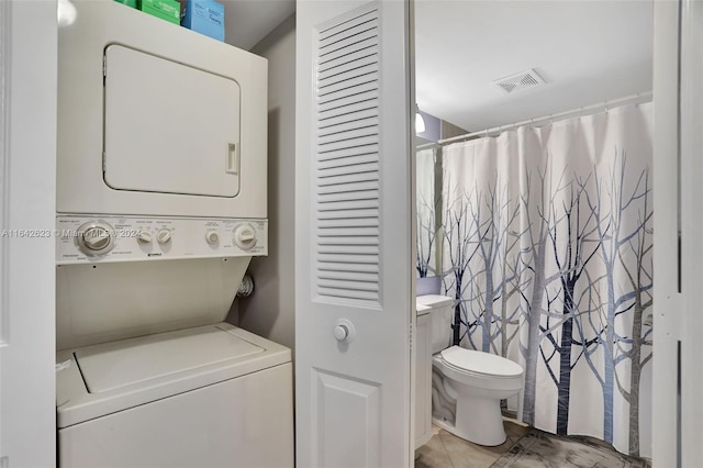 washroom with stacked washer and clothes dryer and light tile patterned floors