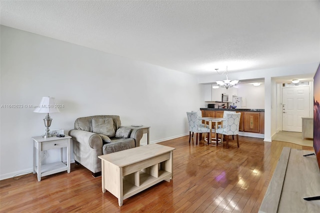 living room featuring hardwood / wood-style flooring, a notable chandelier, and a textured ceiling