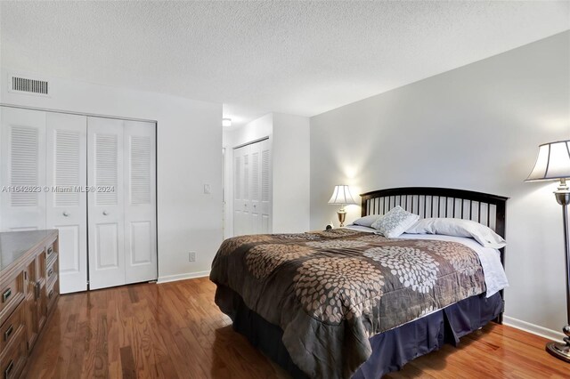 6219 Coral Lake Dr Unit 207, Margate, FL 33063 - bedroom with two closets, baseboards, a textured ceiling, visible vents, and wood finished floors