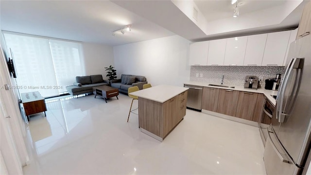 kitchen with a center island, stainless steel appliances, sink, rail lighting, and white cabinets