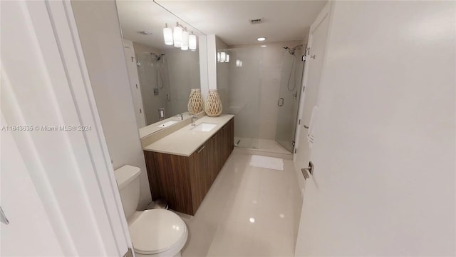 bathroom featuring tile patterned flooring, a shower with shower door, toilet, and vanity