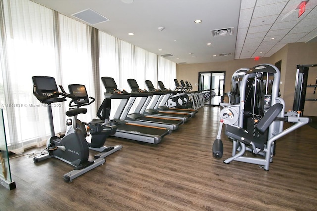 exercise room with dark hardwood / wood-style floors and a drop ceiling