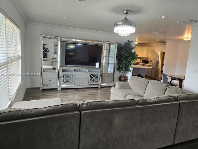 living room with hardwood / wood-style floors, a notable chandelier, and ornamental molding