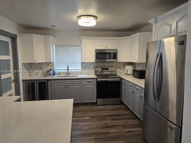 kitchen with sink, gray cabinetry, white cabinets, and appliances with stainless steel finishes