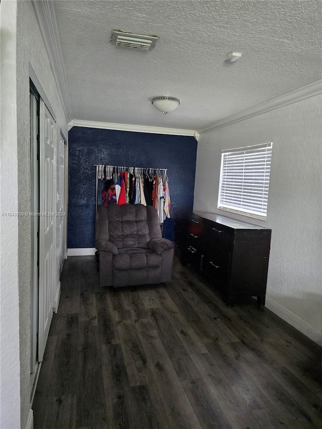 living area with a textured wall, visible vents, dark wood finished floors, and ornamental molding