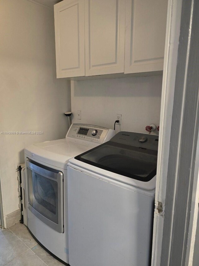 laundry room with washing machine and dryer, cabinets, and light tile patterned flooring