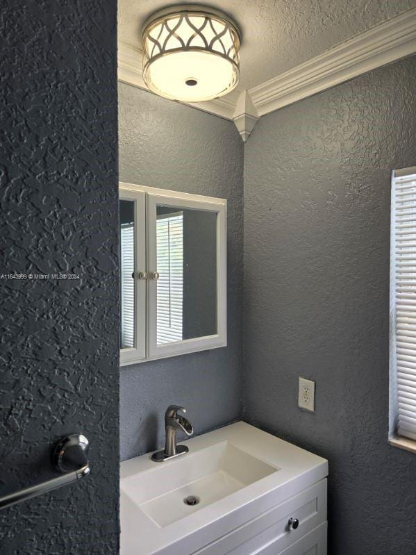 bathroom with a textured ceiling, crown molding, and vanity