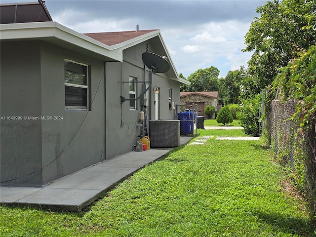 view of home's exterior featuring stucco siding, central air condition unit, a yard, and fence