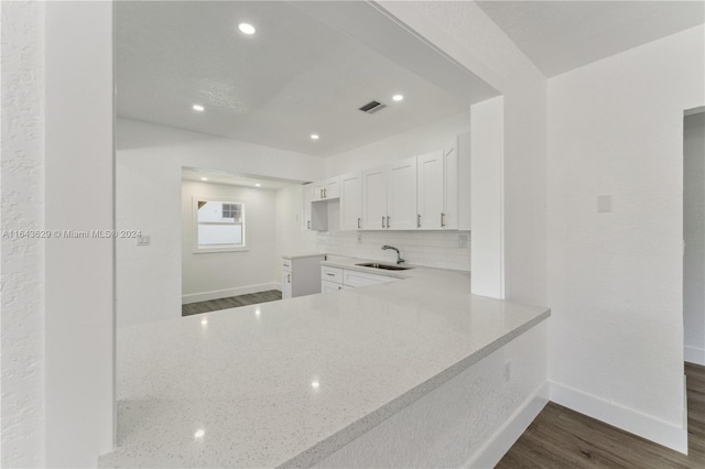 kitchen with white cabinetry, sink, light stone counters, and dark hardwood / wood-style flooring