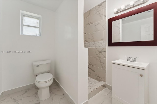 bathroom featuring a tile shower, toilet, and vanity