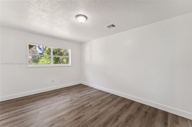 unfurnished room with a textured ceiling and hardwood / wood-style flooring