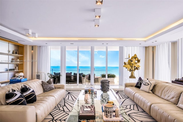 living room with a water view and a raised ceiling